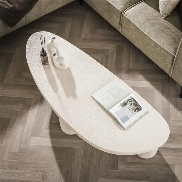 Table basse blanche design triangulaire avec des accessoires décoratifs